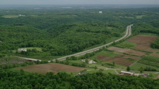 AX107_128 - 4.8K aerial stock footage of an interstate bordered by forests and farmland, Beaver Falls, Pennsylvania