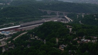 AX108_008 - 4K aerial stock footage approaching a factory and bridge surrounded by trees, East Pittsburgh, Pennsylvania