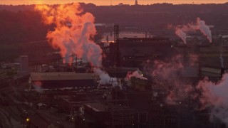 AX108_019E - 4K aerial stock footage of U.S. Steel Mon Valley Works and smoke stacks, Braddock, Pennsylvania, sunset