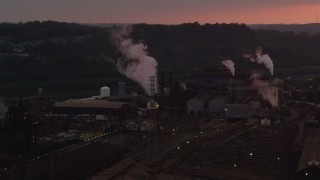AX108_024 - 4K aerial stock footage passing buildings at the U.S. Steel Mon Valley Works, Braddock, Pennsylvania, sunset
