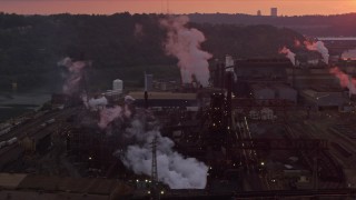 AX108_024E - 4K aerial stock footage passing buildings at the U.S. Steel Mon Valley Works, Braddock, Pennsylvania, sunset