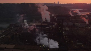 AX108_026 - 4K aerial stock footage of smoke rising from the U.S. Steel Mon Valley Works, Braddock, Pennsylvania, sunset