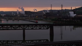 AX108_031E - 4K aerial stock footage of U.S. Steel Mon Valley Works viewed from a bridge, Braddock, Pennsylvania, sunset