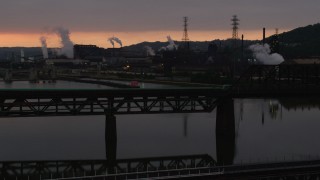 AX108_032 - 4K aerial stock footage of the U.S. Steel Mon Valley Works seen from a bridge, Braddock, Pennsylvania, sunset