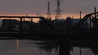 AX108_033 - 4K aerial stock footage of U.S. Steel Mon Valley Works seen through a bridge, Braddock, Pennsylvania, sunset
