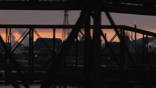 AX108_034 - 4K aerial stock footage of U.S. Steel Mon Valley Works seen through a bridge, Braddock, Pennsylvania, sunset