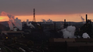 AX108_035 - 4K aerial stock footage of rising smoke from the U.S. Steel Mon Valley Works, Braddock, Pennsylvania, sunset