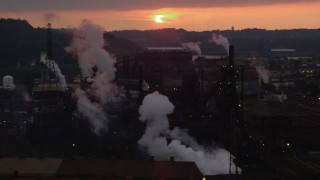 AX108_036 - 4K aerial stock footage of rising smoke from the U.S. Steel Mon Valley Works, Braddock, Pennsylvania, sunset