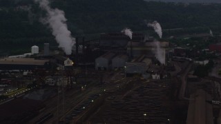 AX108_038 - 4K aerial stock footage of smoke rising from the U.S. Steel Mon Valley Works, Braddock, Pennsylvania, twilight