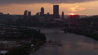 AX108_052E - 4K aerial stock footage of Downtown Pittsburgh skyline seen from the Monongahela River, Pennsylvania, sunset