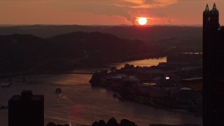 AX108_061E - 4K aerial stock footage setting sun seen while flying by skyscrapers, reveal West End Bridge, Pittsburgh, Pennsylvania, sunset
