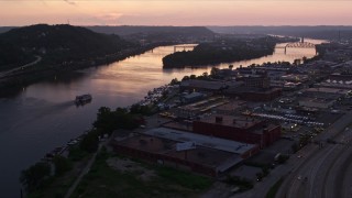 AX108_089E - 4K aerial stock footage approaching warehouses along Ohio River, Pittsburgh, Pennsylvania, twilight