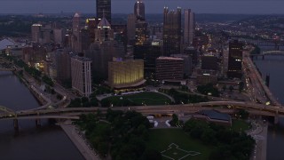 AX108_111E - 4K aerial stock footage of Fort Duquesne at Point State Park, Downtown Pittsburgh skyscrapers, Pennsylvania, twilight