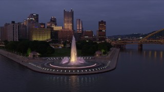 AX108_122E - 4K aerial stock footage flying by Downtown Pittsburgh skyscrapers revealing Point State Park, Pennsylvania, twilight