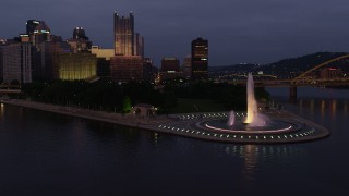 AX108_123 - 4K aerial stock footage flying by Point State Park Fountain, Downtown Pittsburgh, Pennsylvania, twilight