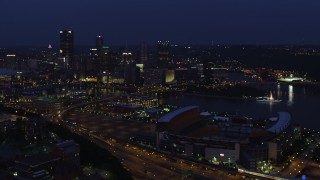 AX108_160 - 4K aerial stock footage flying toward Downtown Pittsburgh passing Heinz Field, Pennsylvania, night