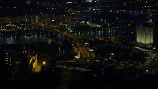 AX108_197E - 4K aerial stock footage of Point State Park and skyscrapers seen from church, Downtown Pittsburgh, Pennsylvania, night