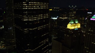AX108_224E - 4K aerial stock footage passing by city buildings, Gulf Tower and U.S. Steel Tower, Pittsburgh, night