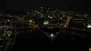 AX108_235E - 4K aerial stock footage flying over Point State Park Fountain toward Downtown Pittsburgh, Pennsylvania, night