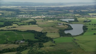 AX109_004 - 5.5K aerial stock footage of green farms and a reservoir, Denny, Scotland