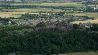 AX109_019E - 5.5K aerial stock footage of Stirling Castle atop a tree-covered hill in Scotland