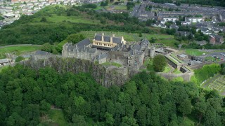 AX109_038 - 5.5K stock footage aerial video of passing Stirling Castle atop a tree covered hill, Scotland