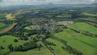 AX109_065 - 5.5K aerial stock footage approach rural village beside green farmland, Scotland