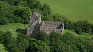 AX109_070E - 5.5K aerial stock footage of orbiting Doune Castle with tourists on the grounds, Scotland
