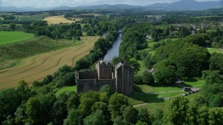 AX109_076 - 5.5K stock footage aerial video fly over Doune Castle and River Teith line with trees, Scotland