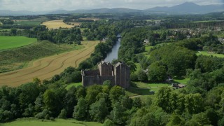 AX109_076E - 5.5K aerial stock footage fly over Doune Castle and River Teith line with trees, Scotland