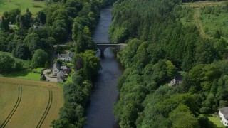 AX109_078E - 5.5K aerial stock footage tilt to bird's eye of RV and white car on a bridge over River Teith lined with trees, Duone, Scotland