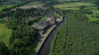 AX109_080 - 5.5K aerial stock footage of approaching a riverfront factory by River Teith, Doune, Scotland