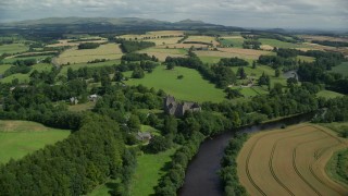 AX109_087 - 5.5K aerial stock footage of flying over historic Doune Castle toward farmland, Scotland