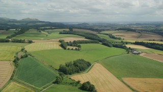 AX109_089E - 5.5K aerial stock footage of flying over farm fields and trees, Doune, Scotland