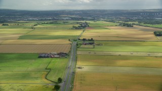 AX109_114E - 5.5K aerial stock footage fly over roundabout on A905 highway by farm fields, Falkirk, Scotland