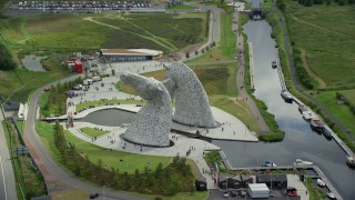 AX109_124E - 5.5K aerial stock footage of orbiting The Kelpies sculptures with tourists in Falkirk, Scotland