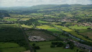 AX109_169E - 5.5K aerial stock footage of farm fields and highway M80 by rural village homes, Bonnybridge, Scotland