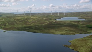 AX110_019 - 5.5K stock footage aerial video fly over Earlsburn Reservoirs by windmills, Scotland