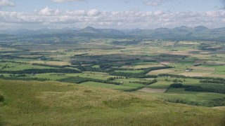 AX110_027 - 5.5K aerial stock footage fly over hills to approach Carleatheran, reveal farm fields, Scotland