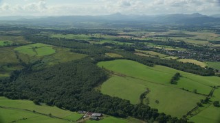 AX110_029E - 5.5K aerial stock footage of forests and farm fields, Kippen, Scotland