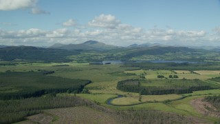 AX110_037E - 5.5K aerial stock footage of Lake of Menteith beside forest and mountains, Scotland