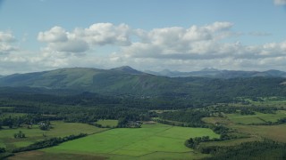 AX110_040E - 5.5K aerial stock footage video of farms, forest and mountains near Aberfoyle, Scotland