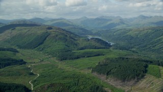 AX110_045E - 5.5K aerial stock footage of tree-covered mountains around Loch Chon, Scottish Highlands  Scotland