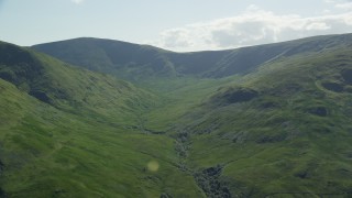 AX110_100 - 5.5K aerial stock footage of passing lush green mountains, Scottish Highlands, Scotland