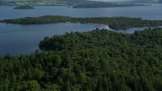 AX110_108E - 5.5K aerial stock footage fly over small island beach with trees, Loch Lomond, Scottish Highlands, Scotland
