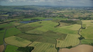 AX110_219E - 5.5K aerial stock footage approach farming fields and rural neighborhoods outside of Glasgow, Scotland