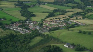 AX110_233 - 5.5K aerial stock footage of rural homes surrounded by farmland, Cumbernauld, Scotland