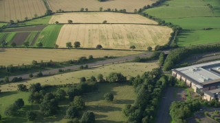AX111_024E - 5.5K aerial stock footage of tracking a black car on M9 Highway through farmland, Linlithgow, Scotland