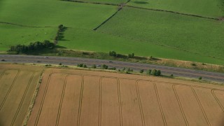 AX111_025 - 5.5K aerial stock footage of tracking a black Car on M9 Highway through farmland, Linlithgow, Scotland