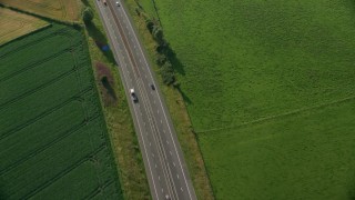 AX111_026 - 5.5K aerial stock footage of tracking a black car on M9 Highway through farmland, Linlithgow, Scotland